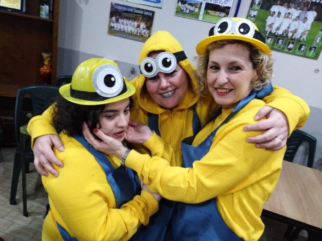 Tre persone vestite da Minion che si abbracciano sorridendo.