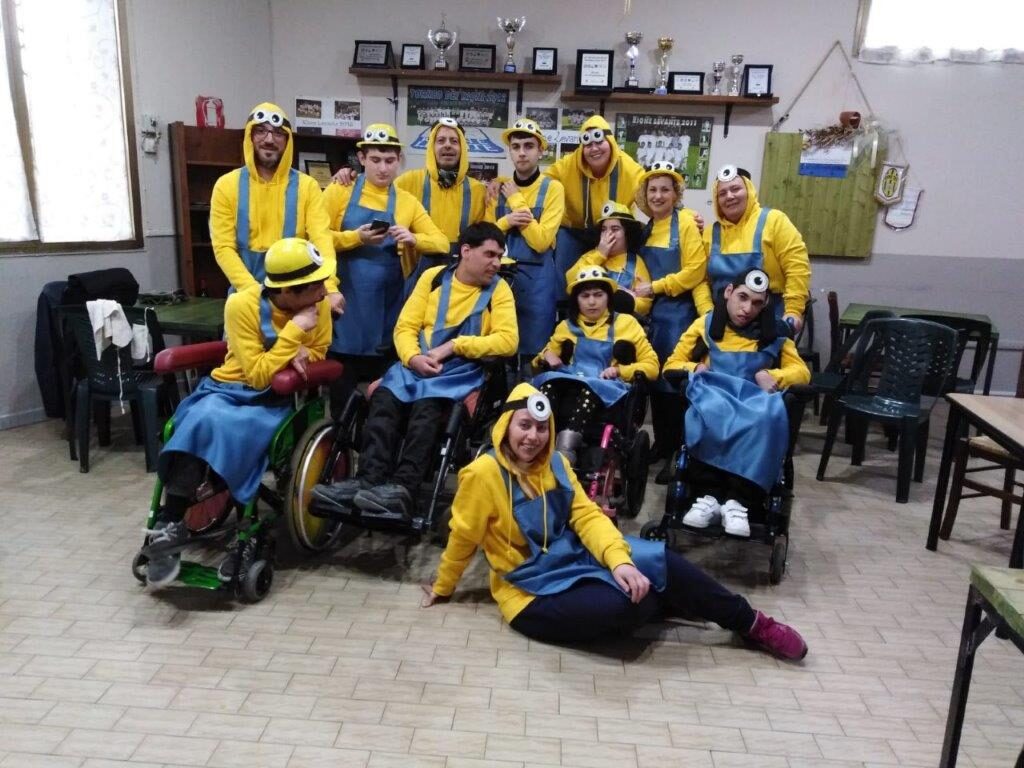 Un gruppo di ragazzi e volontari vestiti da Minion, alcuni in carrozzina, in posa tutti insieme.