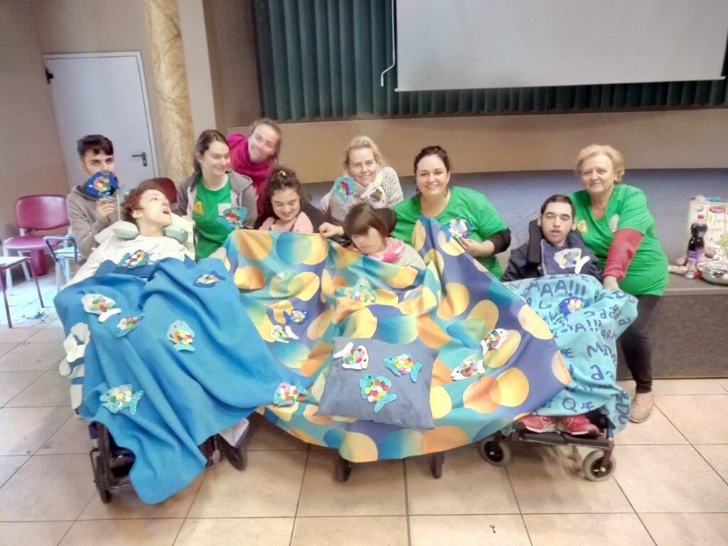 Ragazzi e volontari seduti vicini, coperti da grandi coperte colorate.