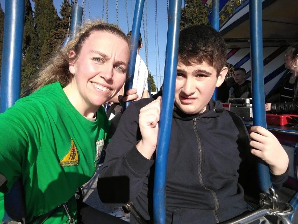 Una volontaria e un ragazzo seduti sulla giostra delle catene, pronti a partire.